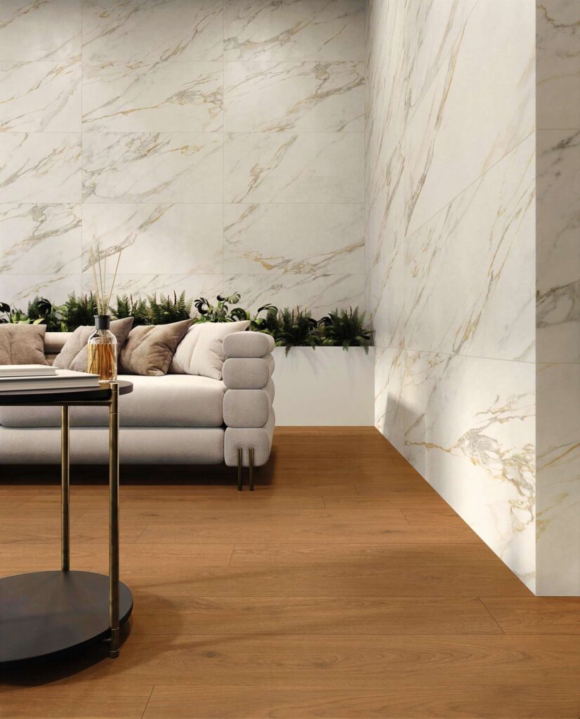 Salon moderne avec carrelage mural effet marbre blanc et doré, sol en parquet bois et canapé gris élégant.
