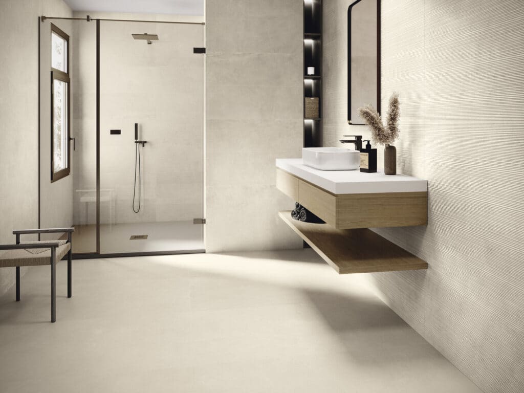 Salle de bain beige moderne, douche à l'italienne, meuble bois flottant et mur texturé.