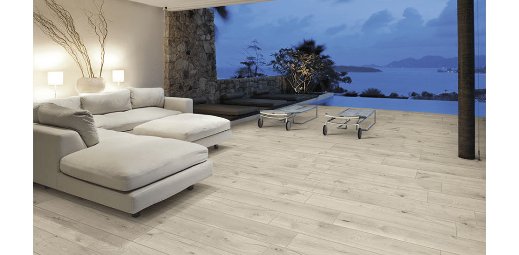 Terrasse en carrelage imitation bois clair au bord d'une piscine à débordement, avec vue sur la mer et les îles au crépuscule.